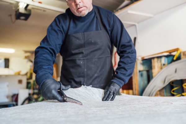 Fiberglass roving; Adult person cutting a fiberglass.